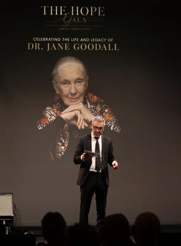 Speaker on stage at The Hope Gala in front of a portrait of Dr Jane Goodall
