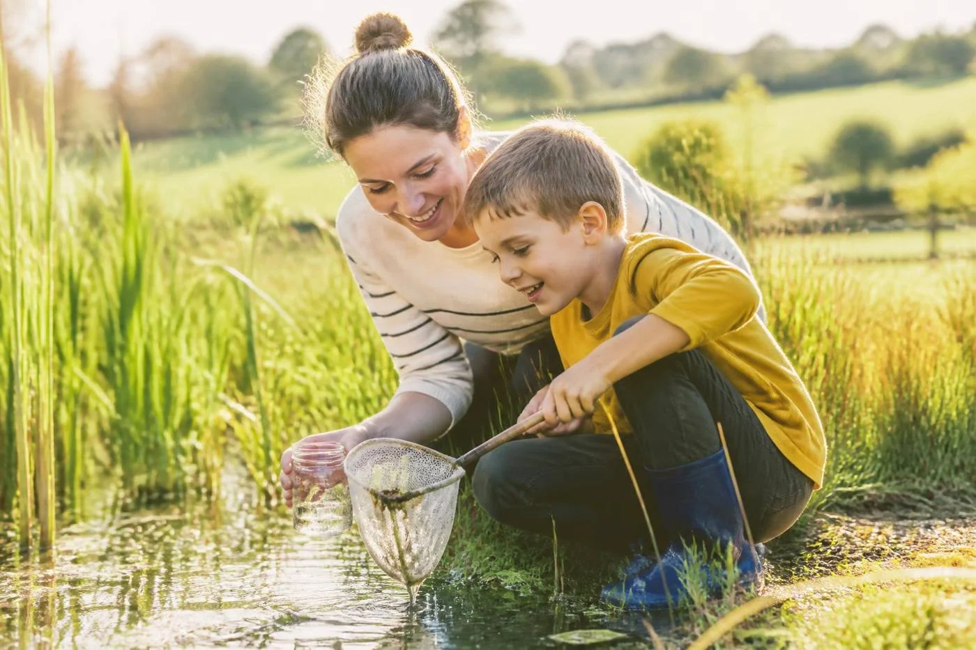 A parent and child pond dipping with a net in the countryside
